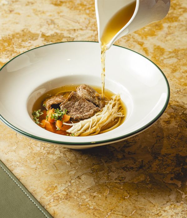 Beef consommé with vegetables, enoki mushrooms and rice noodles