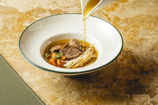 Beef consommé with vegetables, enoki mushrooms and rice noodles